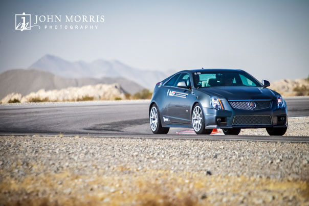 A sleek, black Cadillac races out of a tight corner during a commercial shoot at a test track in Nevada.