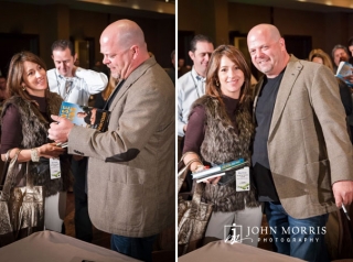 Rick Harrison, signs a book and poses with an attendee during a corporate event.