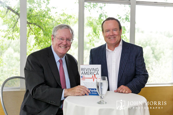 Steve Forbes and Executive smiling and posing for the camera during a book signing event.