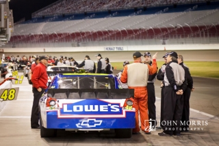A line of stock cars and attendees in the pit area during a corporate outing at the Las Vegas Motor Speedway.