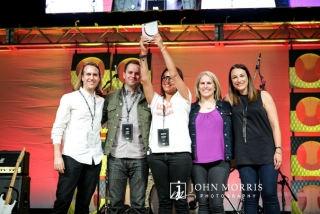 Group of five award winners celebrating on stage during a corporate awards ceremony.