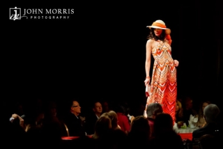 Model paused on a catwalk, bathed in red light during an apparel convention