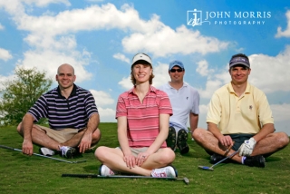 Four golfers posing for the camera on a golf course sitting yoga style for a corporate event.