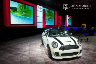 An white automobile highlights an elaborate stage set up for an upcoming keynote during a corporate event.