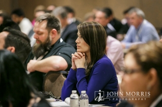 Woman listens intently from her seat to a presentation during a corporate breakout session