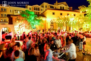 An outdoor venue, with a greek island feel, is bathed with light and full of happy attendees during a networking event.