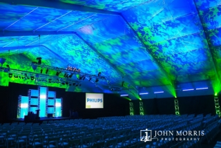 Large venue tent and stage are dramatically lit in preparation for keynote and corporate event.