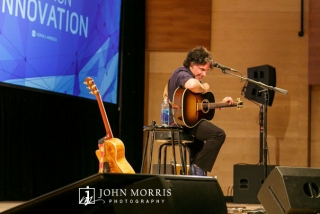 John Oates performing on stage, unplugged, with guitar for a corporate event attendees in an intimate setting.