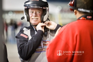 Executive donning a racing helmet and wearing a smile during a corporate outing at the Las Vegas Motor Speedway.