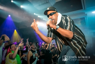 Ton Loc performing on stage for an energetic corporate event crowd.