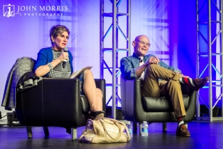 A serious Mary Matalin and jovial James Carville addressing a conference crowd