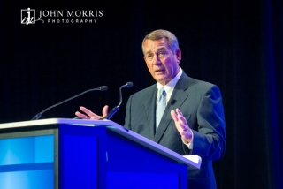 Expressive House Speaker John Boehner on stage speaking during a conference.