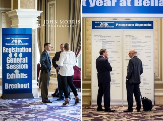 Groups of professionals networking and sharing ideas in front of registration and agenda signage during a corporate event