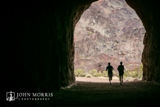 Silhouette of two runners entering an old railroad tunnel during an corporate sponsored 5k event.
