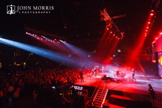 Wide view of band and large crowd bathed in red stage lights performing during a corporate event