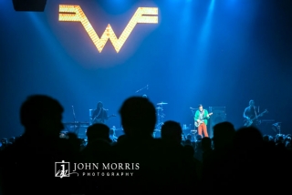 View of Weezer performing on stage from the crowd perspective during a corporate event