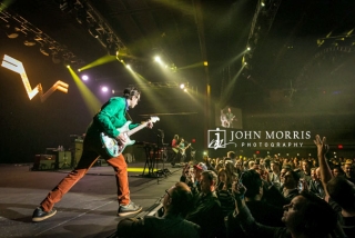 Weezer lead guitarist, on stage and interacting with the crowd during a corporate event