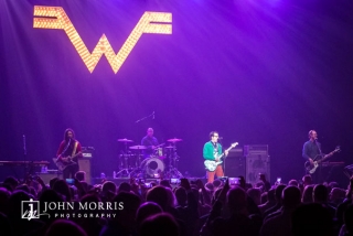 Weezer performing on stage of large crowd during a corporate event