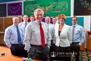 A CEO flanked by his to executives poses in front of roulette table designs his company creates.
