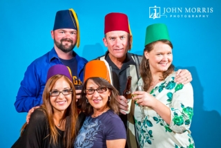 A group of colleagues, poses for a portrait on a blue background, photo booth style, during a corporate networking event.